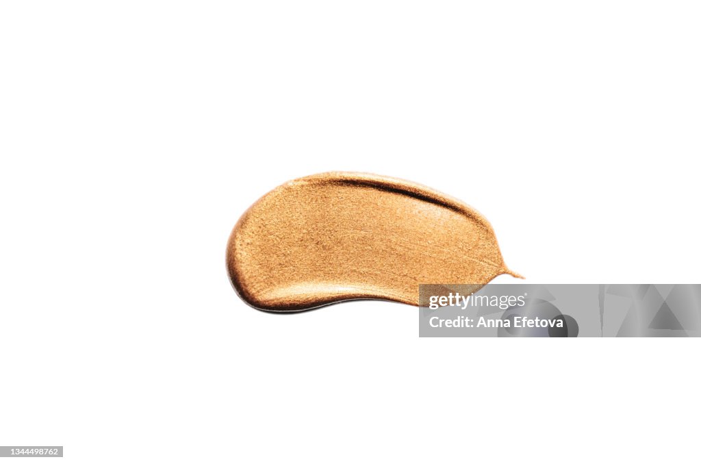 Textured smear of gold eyeshadows with glittering particles. Body lotion with shimmer or sunscreen oil for perfect tan. Macrophotography in flat lay style