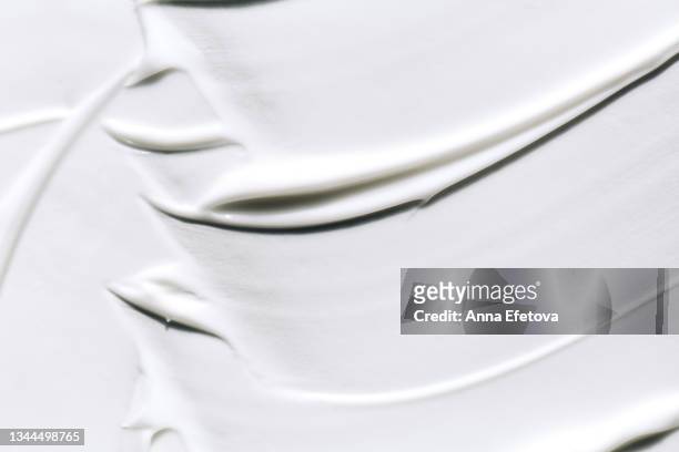 background made with textured smears of white cream. body lotion for perfect skin. copy space for your design. macrophotography in flat lay style - couleur crème photos et images de collection