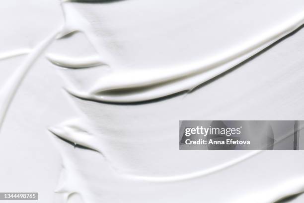 background made with textured smears of white cream. body lotion for perfect skin. copy space for your design. macrophotography in flat lay style - crema foto e immagini stock