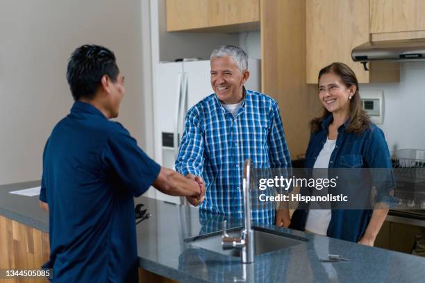 klempner begrüßt glückliche kunden zu hause mit einem handschlag - rohrbruch stock-fotos und bilder