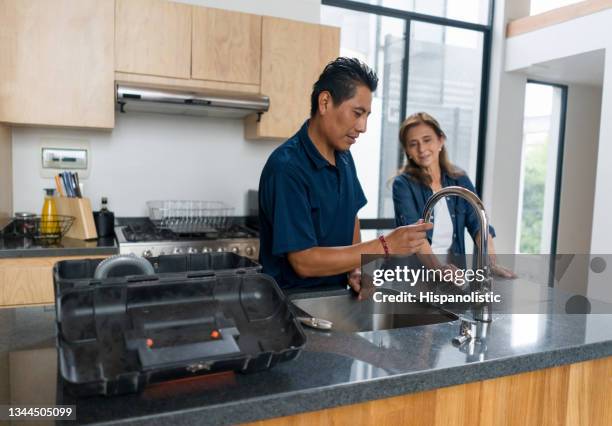 frau zu hause spricht mit einem klempner, der ihre küche repariert - rohrbruch stock-fotos und bilder
