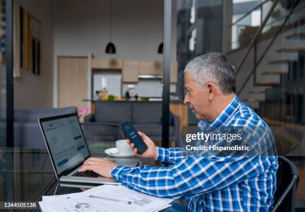 man at home paying bills online using the electronic banking platform on his devices - pact for mexico stock pictures, royalty-free photos & images