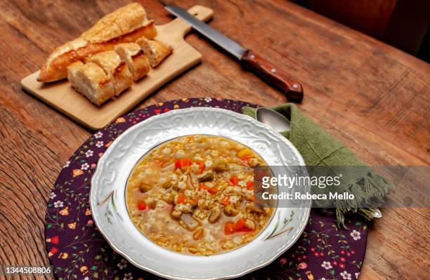 a homemade  soup of assorted vegetables with noodles is served at the table, accompanied by italian-style bread. - winter vegetables stock pictures, royalty-free photos & images