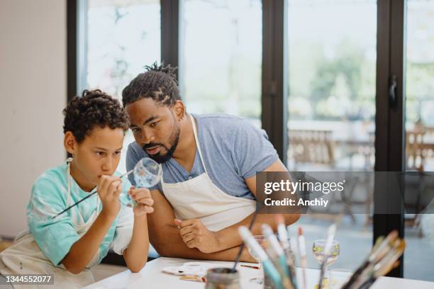 père et fils peignant du verre de vin ensemble lors d’un cours de groupe d’art - atelier enfant photos et images de collection