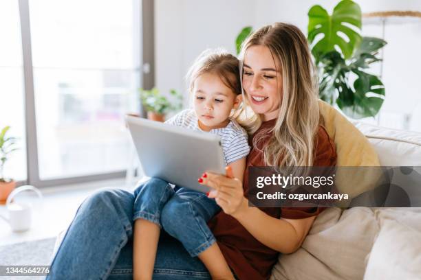 mother and daughter using a digital tablet together - child and ipad stockfoto's en -beelden