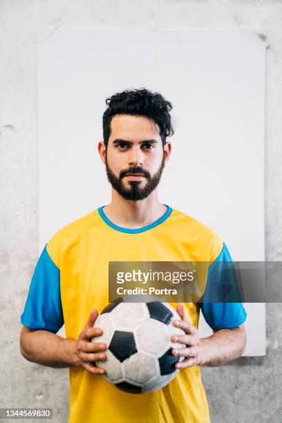ritratto di un giocatore di calcio maschio che tiene una palla - mezzo busto foto e immagini stock