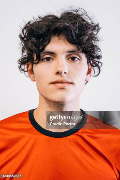 portrait of soccer player standing against white wall - red sports jersey stock pictures, royalty-free photos & images