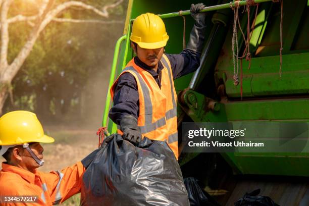 garbage man collecting garbage in the garbage truck at city. - garbage truck stock-fotos und bilder
