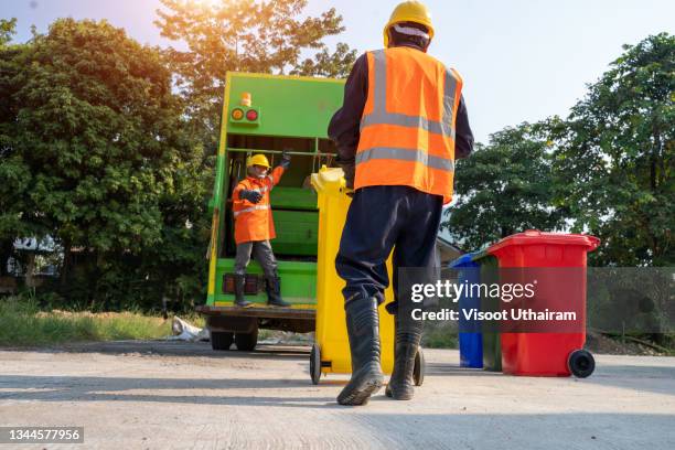 garbage man collecting garbage in the garbage truck at city. - garbage truck stock-fotos und bilder