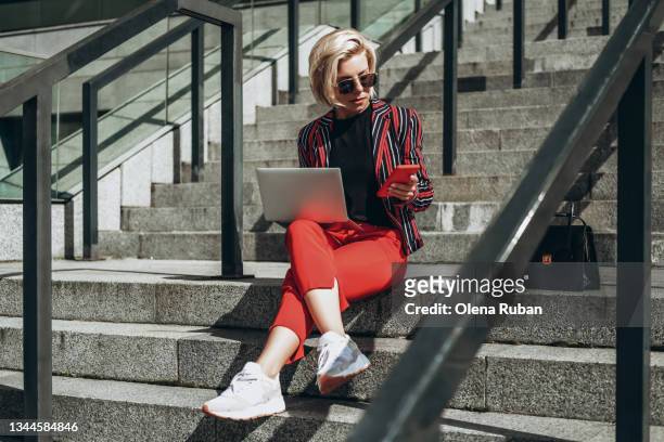 young woman working on laptop sitting on stairs. - fashion blogger stock-fotos und bilder