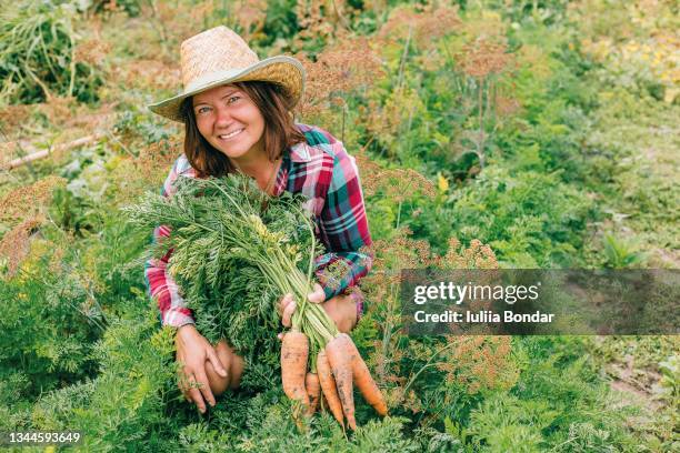 woman with carrot in garden. - agriculture in ukraine stock pictures, royalty-free photos & images