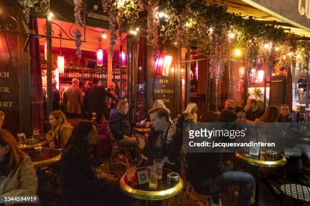 terrace and café near the arc de triomphe in paris in the evening. people are sitting on the terrace talking and drinking - bar paris stockfoto's en -beelden