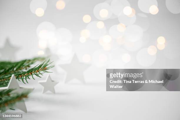 christmas background with fir branches white stars on white background with white stars. fairy lights. - christmas still life - fotografias e filmes do acervo