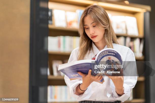 young female student reading a book about business - textbook stock pictures, royalty-free photos & images