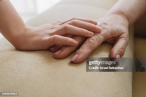 close-up view of an unrecognizable young girl tenderly stroking her grandmother's hand. - arm span stockfoto's en -beelden