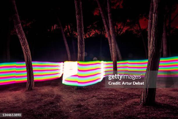 rainbow color ribbon light trail embracing the nature forest at night in futuristic vision - rainbow forrest abstract bildbanksfoton och bilder