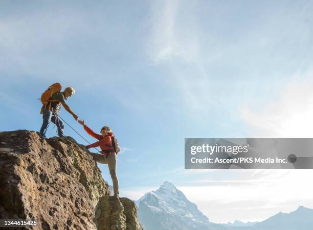 mountaineering couple climb rock face in the swiss alps - klettern stock-fotos und bilder