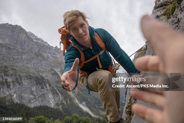young man climbs up rock face in the swiss alps - climbers team stock-fotos und bilder