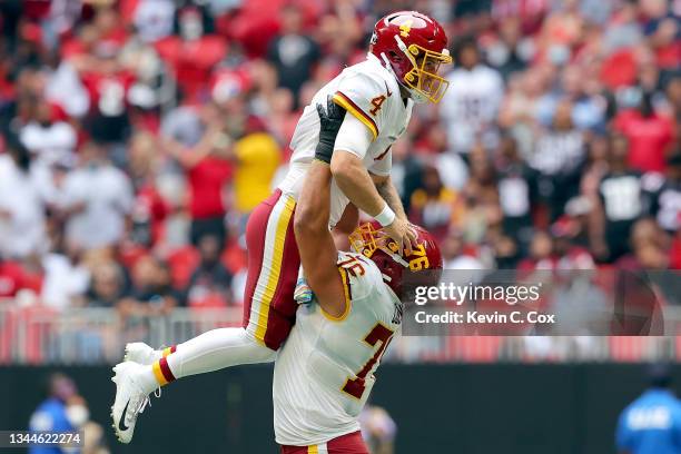 Quarterback Taylor Heinicke of the Washington Football Team is raised up by teammate Sam Cosmi after a touchdown in the second quarter against the...