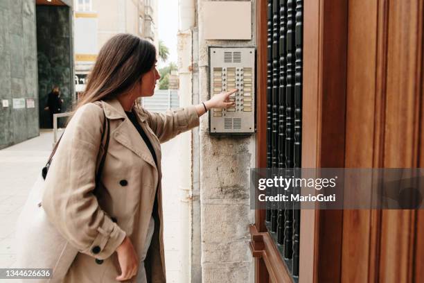 mujer joven tocando el timbre de un apartamento - door bell fotografías e imágenes de stock