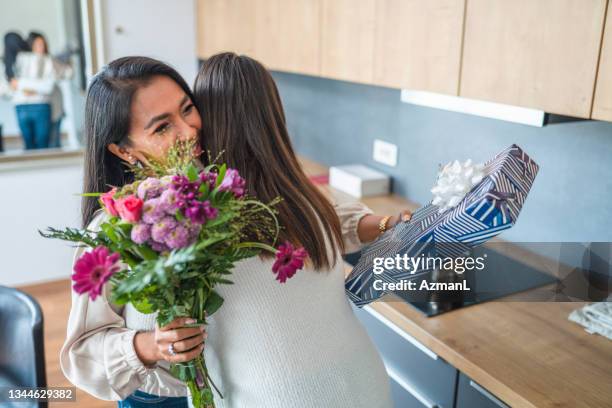 asian mother and teenage daughter embracing and celebrating a birthday - receiving flowers stock pictures, royalty-free photos & images