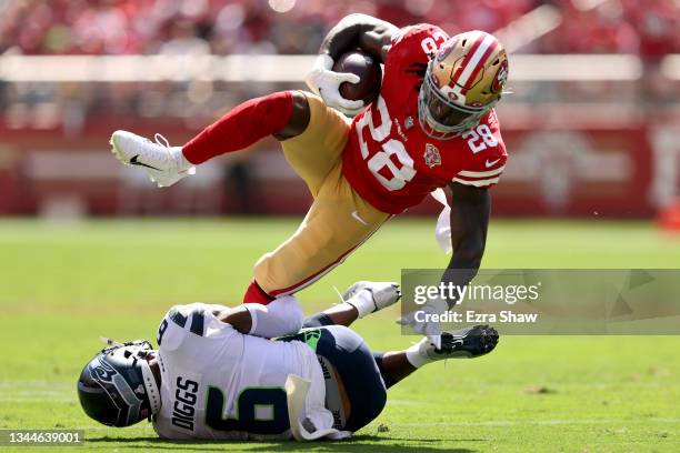Trey Sermon of the San Francisco 49ers dives over Quandre Diggs of the Seattle Seahawks during the first quarter at Levi's Stadium on October 03,...