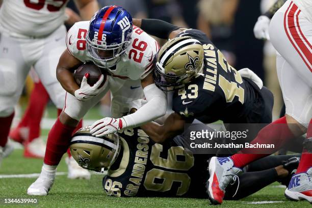Saquon Barkley of the New York Giants is tackled by Carl Granderson and Marcus Williams of the New Orleans Saints during the third quarter at Caesars...