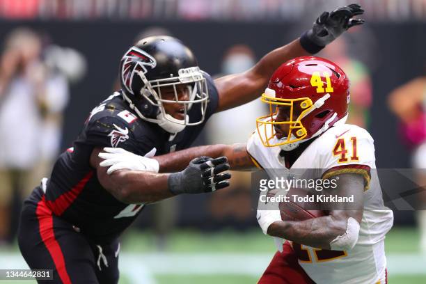 McKissic of the Washington Football Team runs with the ball against Dante Fowler Jr. #6 of the Atlanta Falcons in the fourth quarter at Mercedes-Benz...