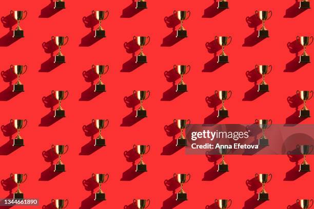 pattern made of metallic golden goblets on red background with shadows. flat lay style - awards ceremony sports stock pictures, royalty-free photos & images