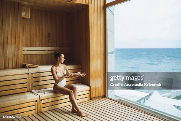 young beautiful multiracial woman making anti cellulite or lymphatic dry massage at  finnish sauna. - natural organic thermo cosmetics foto e immagini stock