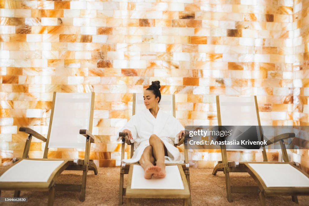 Young beautiful woman in bathrobe relaxing in the salt room in spa centr.