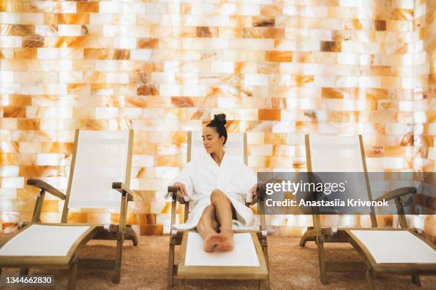 young beautiful woman in bathrobe relaxing in the salt room in spa centr. - salt cave therapy stock pictures, royalty-free photos & images