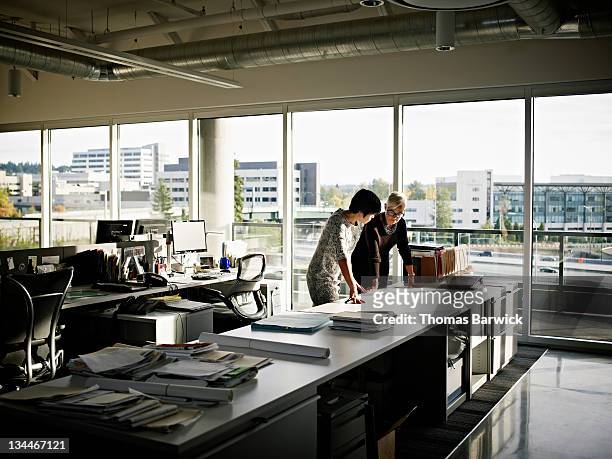 two female architects examining plans in office - asian architect 40 imagens e fotografias de stock