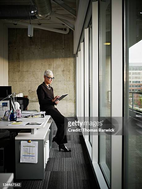 businesswoman using digital tablet in office - white hair stock-fotos und bilder