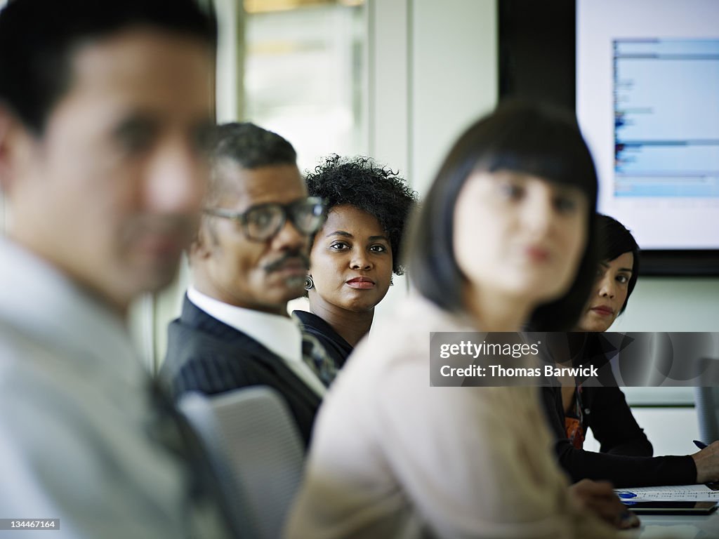 Businesswoman sitting surrounded by coworkers