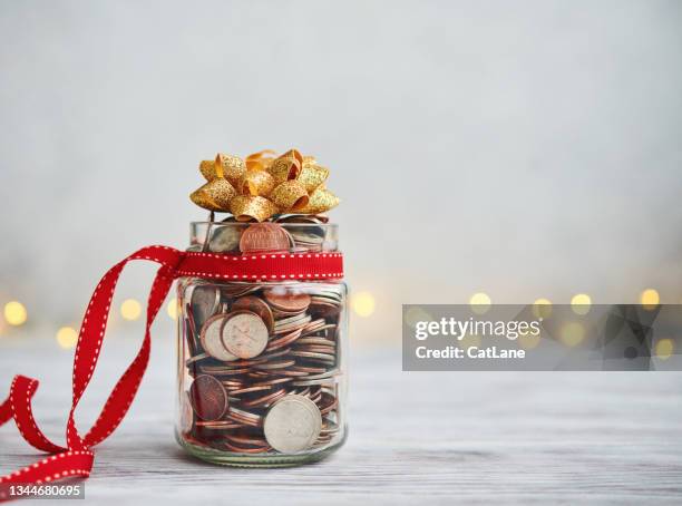 holiday savings jar filled with coins and christmas ribbon and bow - charitable donation stock pictures, royalty-free photos & images