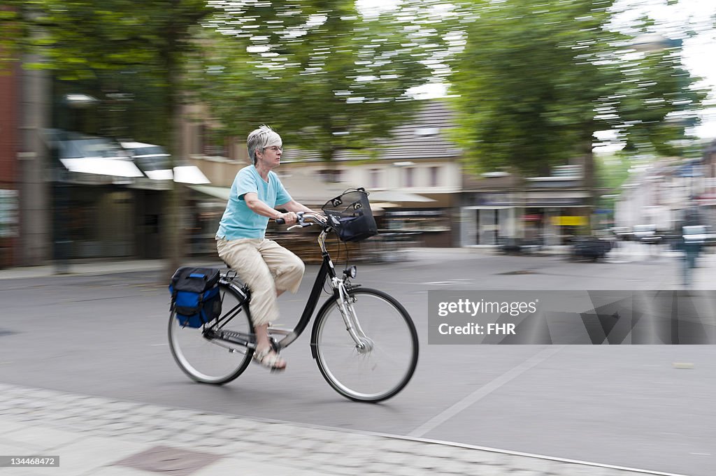 Woman driving her bike across the marketplace, Grevenbroich, North Rhine-Westphalia, Germany, Europe