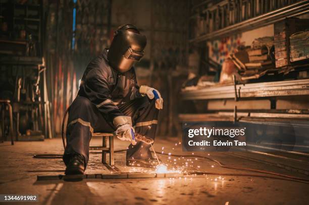 asiatische chinesische schweißerin schweißerin, die in der werkstatt mit schweißbrennerreparatur arbeitet - blacksmith sparks stock-fotos und bilder