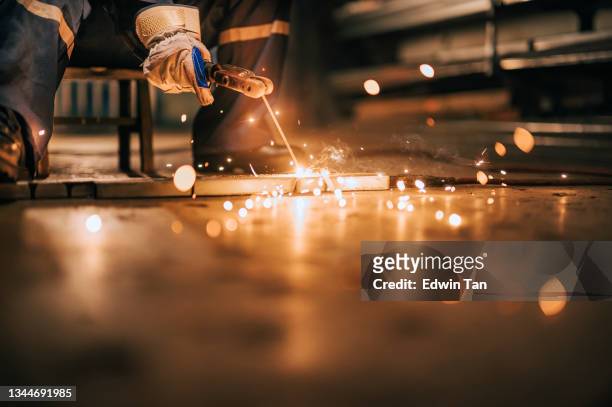 close up asian chinese female welder welding working in the workshop with welding torch repairing - smederij stockfoto's en -beelden