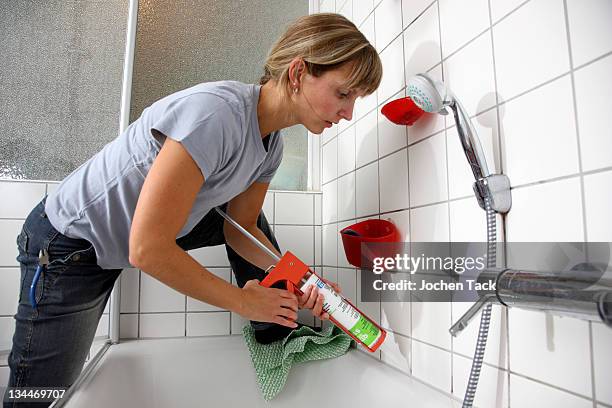 young woman sealing joints with a plastic composition and the help of a sealant gun in a bathroom - silikon stock-fotos und bilder