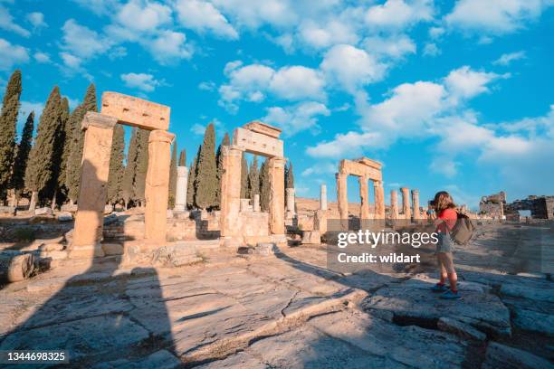 photographer tourist girl is taking photos of the frontinus gate in ancient ruins of hierapolis , pamukkale - hierapolis stock pictures, royalty-free photos & images