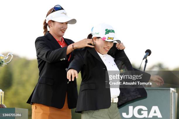 Minami Katsu of Japan is presented the winner's jacket by Erika Hara of Japan at the award ceremony after winning the tournament following the final...