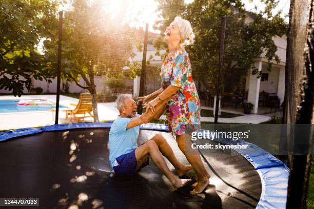 playful senior couple having fun on trampoline at the backyard. - trampoline stock pictures, royalty-free photos & images