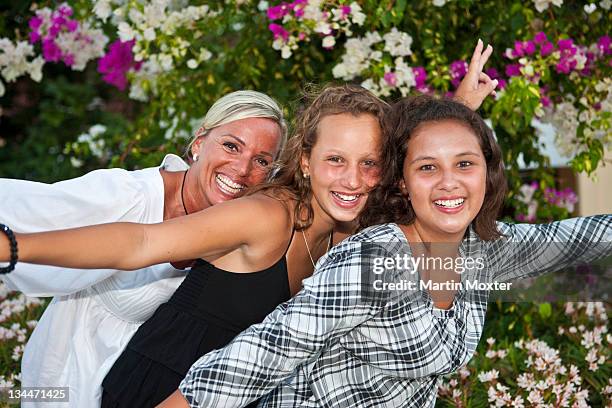 portrait of a mother with two thirteen-year-olds girls in front of flowers - 12 year old blonde girl ストックフォトと画像