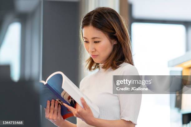 mid adult female reading in the library - international literacy day stock pictures, royalty-free photos & images