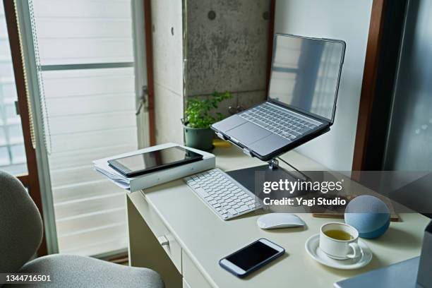 working from home and using a smart speaker - schreibtisch laptop tablet stock-fotos und bilder