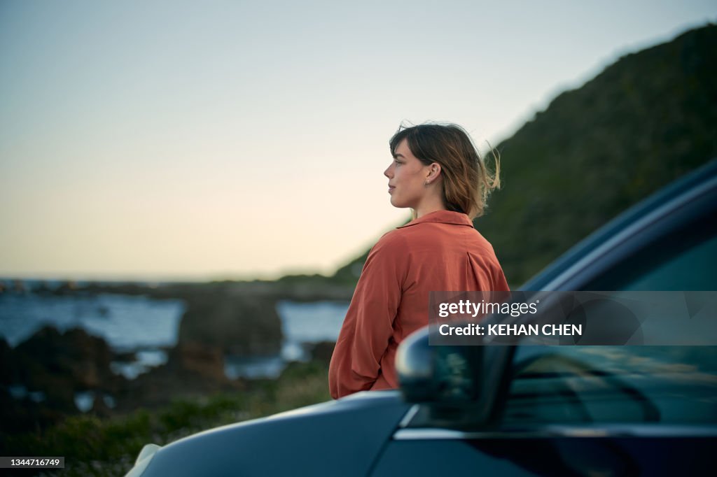 Young girl on the road trip look at beautiful landscape next to the car