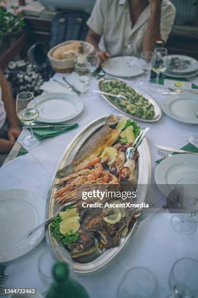 plate of seafood meal and vegetables at an outdoor dining table - croatia food stock pictures, royalty-free photos & images