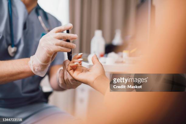 midsection of male doctor measuring blood sugar through glaucometer in clinic - diabetic stockfoto's en -beelden