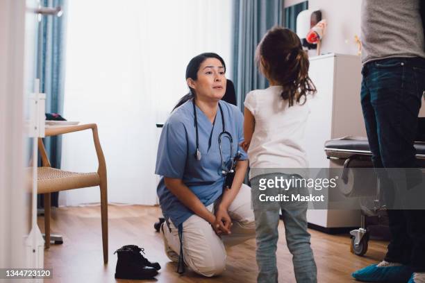 female nurse talking with girl in doctor's office - pediatra foto e immagini stock